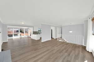 Unfurnished living room with ornamental molding and light wood-style floors