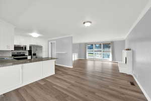 Kitchen with white cabinetry, dark stone counters, open floor plan, appliances with stainless steel finishes, and a peninsula