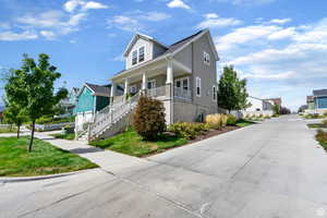 View of front facade featuring stairway, covered porch, a front lawn, and a residential view