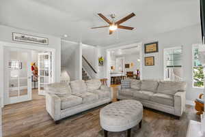 Living room featuring stairway, hardwood / wood-style flooring, ceiling fan, and french doors