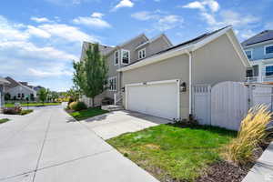 View of side of property with a gate, a residential view, stucco siding, and driveway