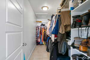 Spacious closet featuring attic access and light tile patterned flooring