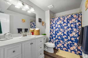 Full bathroom with vanity, curtained shower, a textured ceiling, and dark wood-style flooring