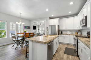 Kitchen featuring appliances with stainless steel finishes, white cabinetry, a center island with sink, decorative backsplash, and recessed lighting