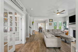 Living area featuring ceiling fan, dark wood-style floors, a fireplace, a textured ceiling, and a chandelier