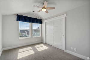 Unfurnished bedroom featuring lofted ceiling, a closet, a ceiling fan, carpet flooring, and a textured ceiling