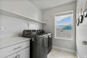 Laundry room featuring light tile patterned flooring, washer and clothes dryer, and cabinet space