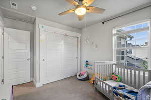 Bedroom with a crib, attic access, a closet, carpet, and ceiling fan