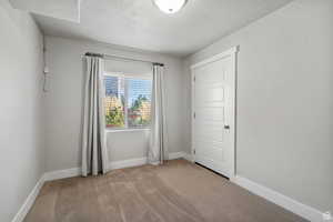 Empty room featuring a textured ceiling and light colored carpet
