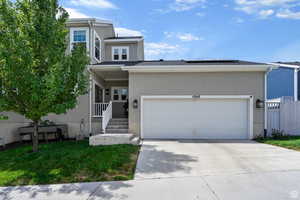 View of front of property with a porch, stucco siding, solar panels, driveway, and a front lawn
