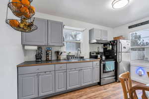 Kitchen with stainless steel range with electric cooktop, tasteful backsplash, gray cabinetry, light wood-style floors, and under cabinet range hood