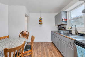 Kitchen with gray cabinetry, light wood-style floors, electric stove, and open shelves