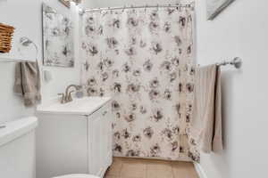 Bathroom featuring a shower with shower curtain, light tile patterned flooring, and vanity