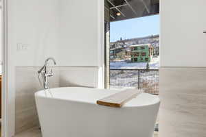 Bathroom with wainscoting, tile walls, and a freestanding bath