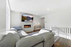Living room with hardwood / wood-style floors, a tiled fireplace, and recessed lighting
