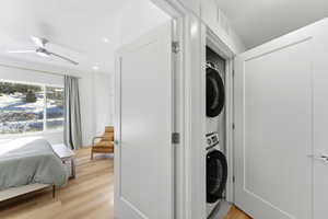 Laundry area featuring light wood-style flooring, stacked washer / dryer, a ceiling fan, and recessed lighting