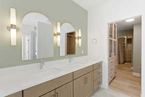 Full bath with double vanity, a shower stall, a spacious closet, and light tile patterned floors