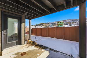 Snow covered patio with a fenced backyard and a patio