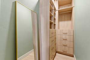 Walk in closet with light wood finished floors