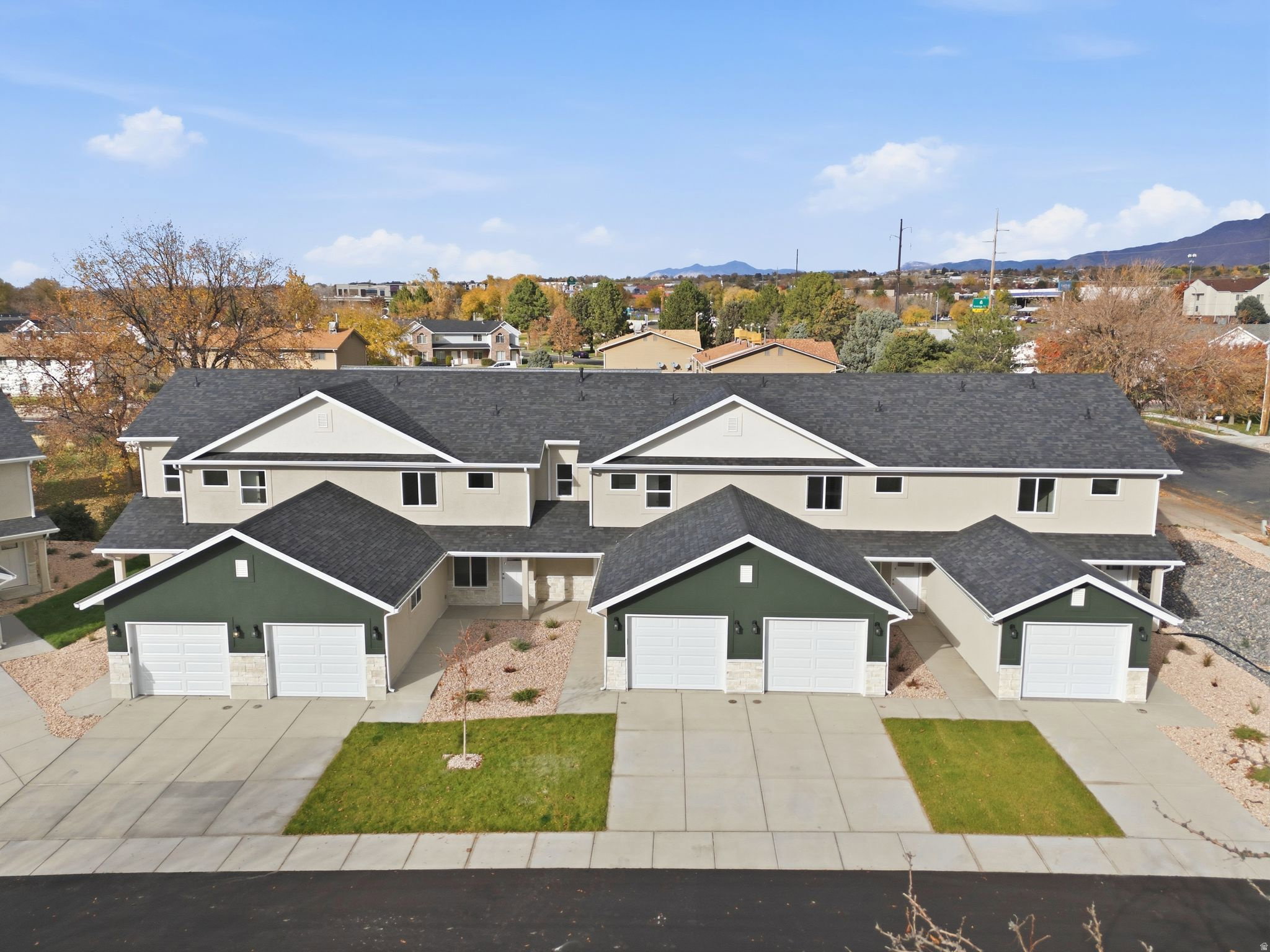 View of front of property featuring stucco siding, driveway, roof with shingles, and a residential view