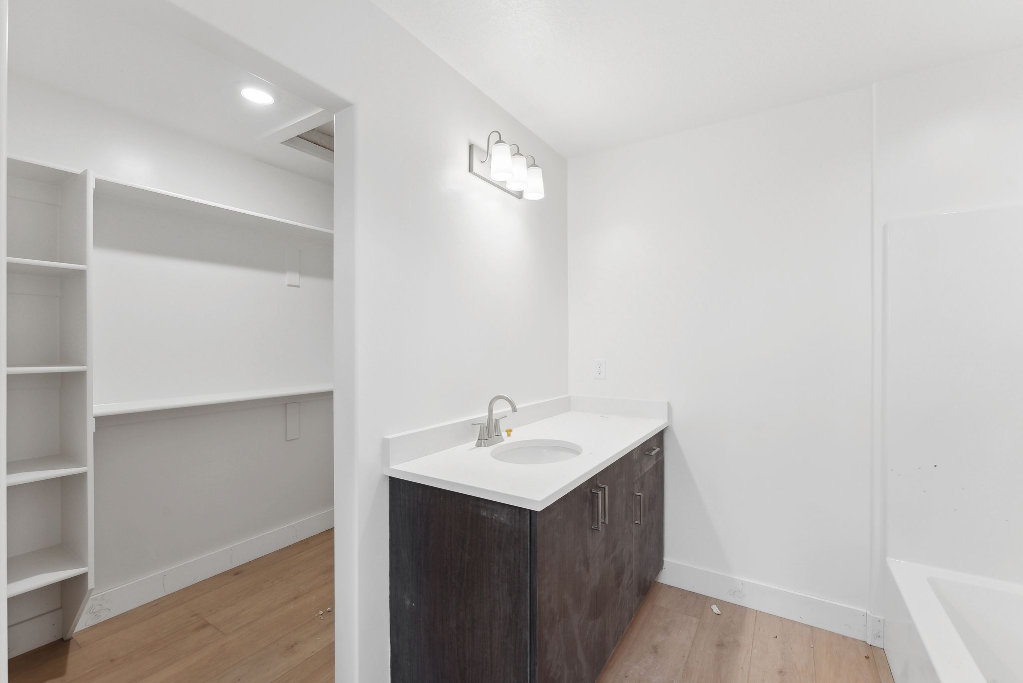 Bathroom with vanity, light wood-style floors, a tub to relax in, a spacious closet, and recessed lighting