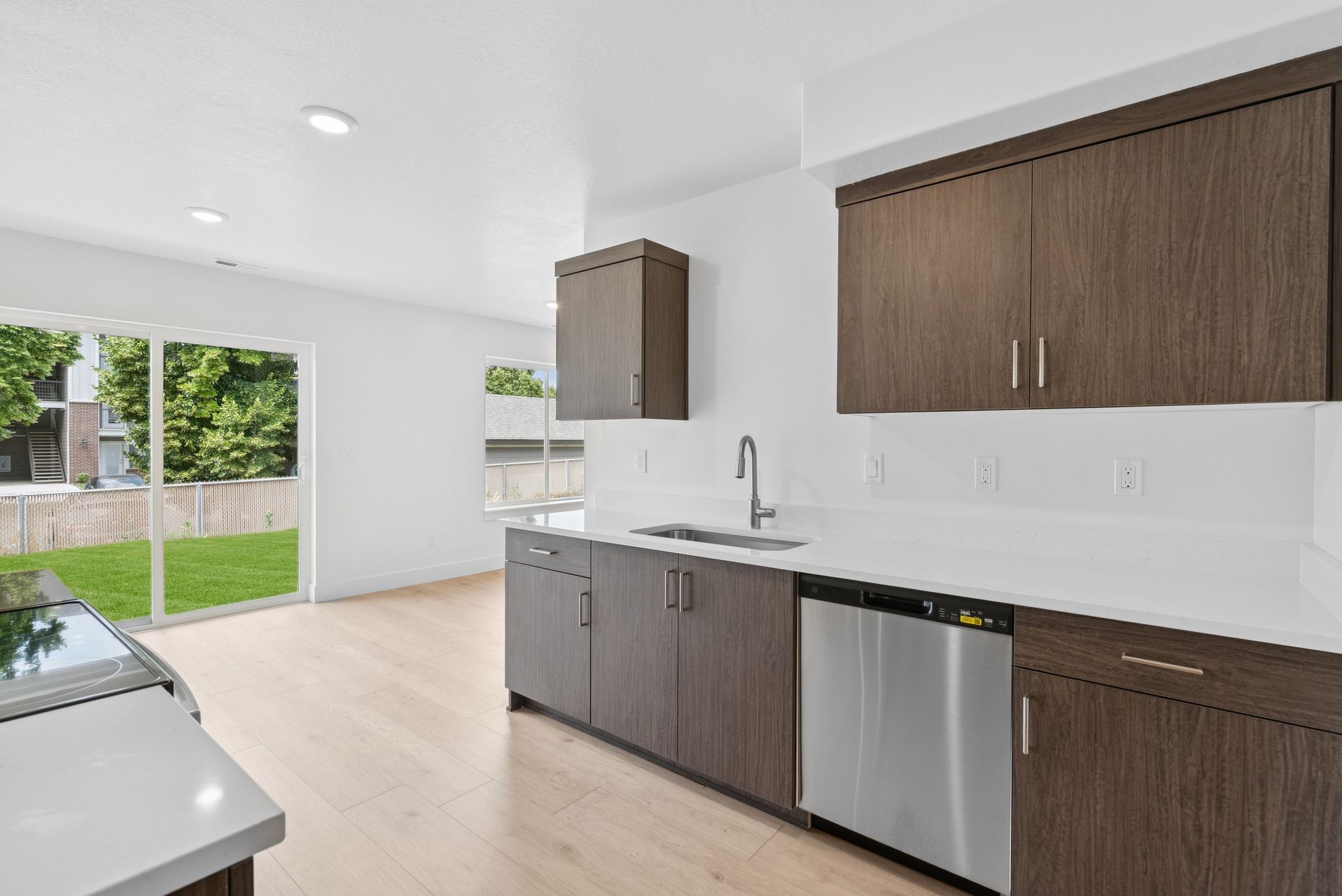 Kitchen with dishwasher, modern cabinets, light stone counters, dark brown cabinets, and recessed lighting