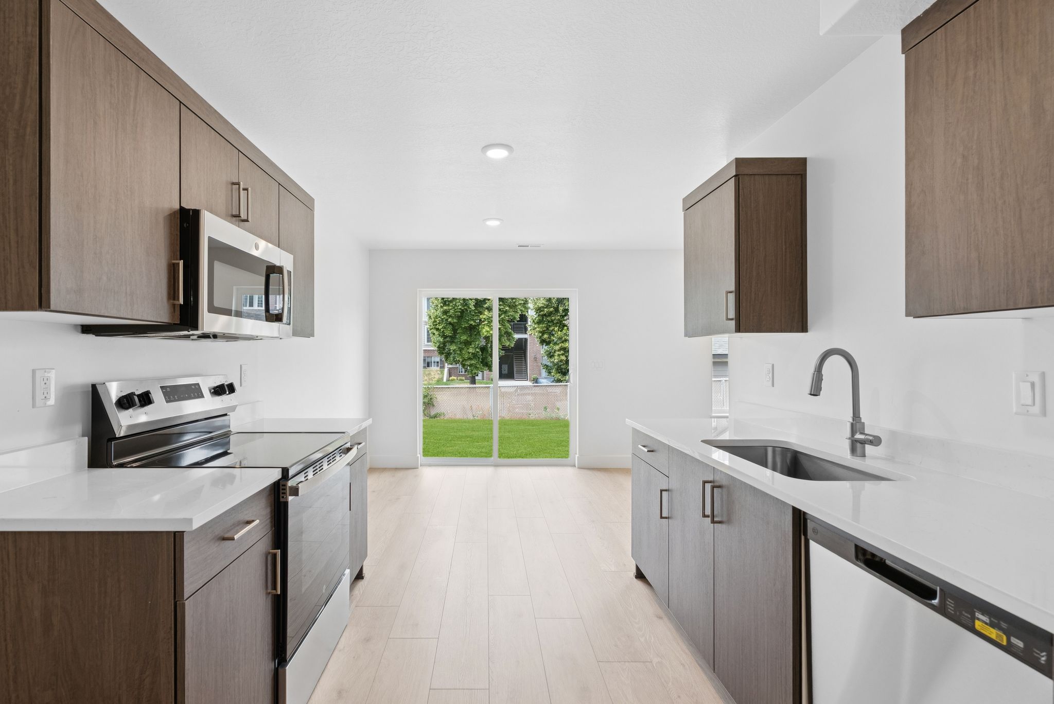Kitchen with appliances with stainless steel finishes, light stone counters, modern cabinets, recessed lighting, and light wood-type flooring