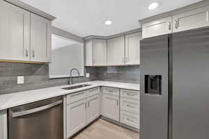 Kitchen with stainless steel appliances, light stone countertops, tasteful backsplash, light wood-style floors, and recessed lighting