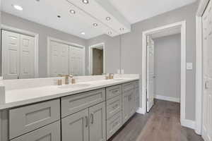 Bathroom with a closet, double vanity, dark wood-style floors, and recessed lighting