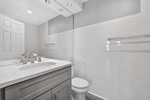 Half bath with vanity and tile walls