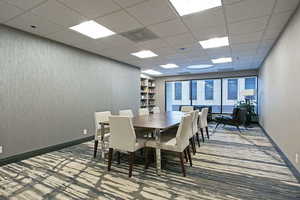 Dining area with a paneled ceiling and wallpapered walls
