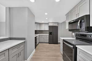 Kitchen featuring black appliances, gray cabinets, recessed lighting, light wood finished floors, and decorative backsplash