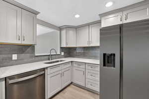 Kitchen featuring stainless steel appliances, light stone counters, light wood-style flooring, recessed lighting, and tasteful backsplash
