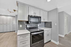 Kitchen featuring electric stove, tasteful backsplash, light stone counters, light wood-type flooring, and recessed lighting