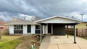 View of front facade with concrete driveway, brick siding, an attached carport, and roof with shingles