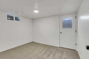 Basement featuring a textured ceiling, carpet flooring, and plenty of natural light