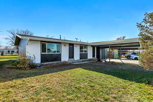 Ranch-style home with brick siding, a front lawn, an attached carport, and roof with shingles