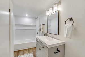 Bathroom with vanity, shower / washtub combination, and light wood-style floors
