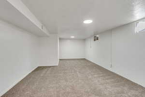 Below grade area with light carpet and a textured ceiling