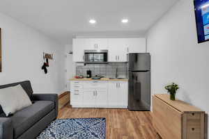 Kitchen with freestanding refrigerator, white cabinets, tasteful backsplash, stainless steel microwave, and recessed lighting
