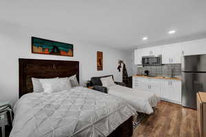 Bedroom featuring freestanding refrigerator, dark wood-style flooring, and recessed lighting
