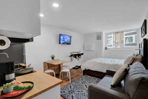 Bedroom featuring wood finished floors, freestanding refrigerator, and recessed lighting