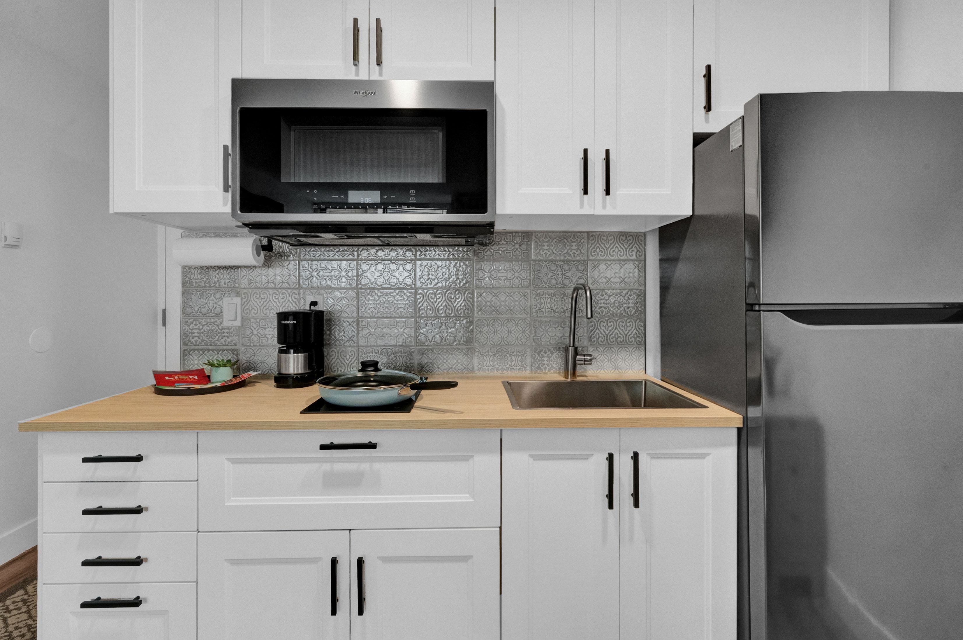 Kitchen with light countertops, appliances with stainless steel finishes, backsplash, and white cabinets