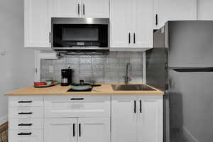 Kitchen with light countertops, appliances with stainless steel finishes, backsplash, and white cabinets
