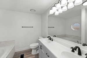 Full bathroom with a garden tub, double vanity, and dark wood-type flooring