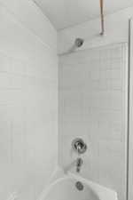 Bathroom view of shower / bath combination and a textured ceiling