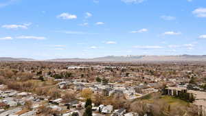 Aerial view of property and surrounding area featuring nearby suburban area and a mountainous background