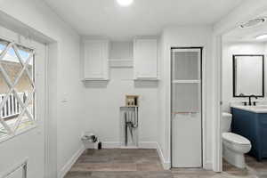 Laundry room featuring a heating unit, washer hookup, light wood-style floors, and cabinet space