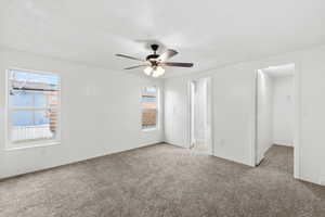 Unfurnished bedroom featuring carpet floors, ceiling fan, a textured ceiling, and ensuite bath