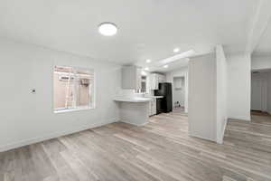 Kitchen with light countertops, white cabinetry, a peninsula, light wood-style floors, and lofted ceiling